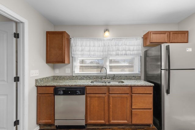 kitchen with light stone counters, appliances with stainless steel finishes, dark wood-type flooring, and sink