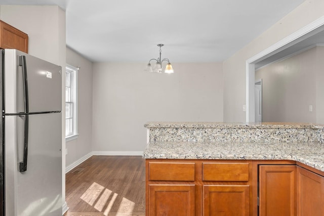 kitchen featuring pendant lighting, light stone counters, dark hardwood / wood-style flooring, and stainless steel refrigerator