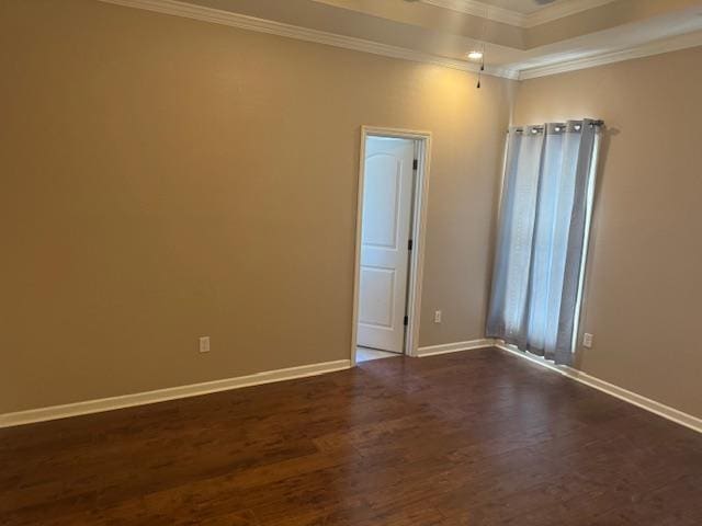 spare room with ornamental molding, a raised ceiling, baseboards, and dark wood-style floors