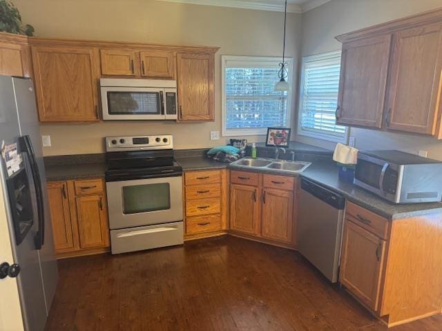 kitchen with appliances with stainless steel finishes, dark countertops, and a sink