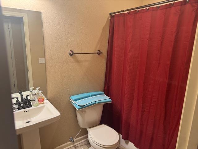 full bath with a sink, toilet, and baseboards