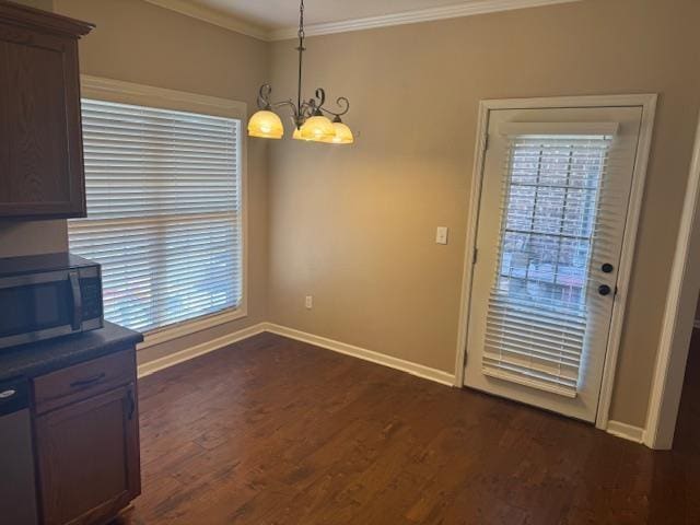 unfurnished dining area featuring crown molding, a notable chandelier, dark wood finished floors, and baseboards