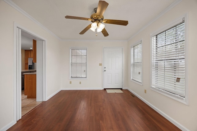 foyer entrance with wood-type flooring, ornamental molding, and a healthy amount of sunlight