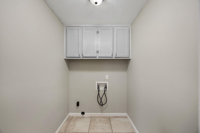 laundry area featuring cabinets, washer hookup, a textured ceiling, and light tile patterned flooring