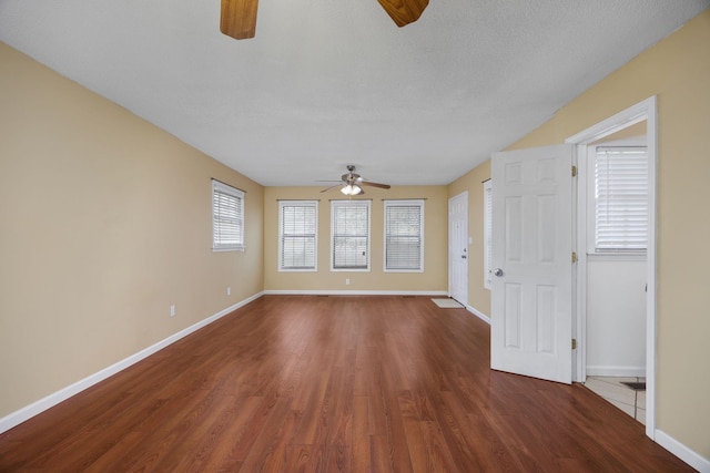 interior space featuring a textured ceiling, ceiling fan, and dark wood-type flooring