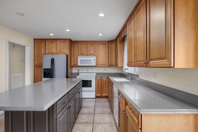 kitchen featuring a center island, white appliances, sink, and light tile patterned floors