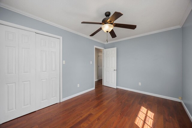 unfurnished bedroom with ceiling fan, crown molding, dark wood-type flooring, and a closet