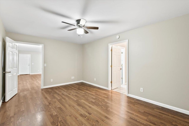empty room featuring baseboards, wood finished floors, and a ceiling fan