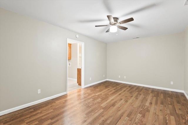 empty room featuring baseboards, visible vents, ceiling fan, and wood finished floors