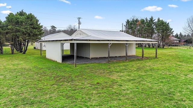 back of house featuring an outbuilding, metal roof, and a yard