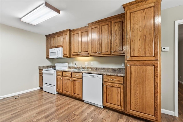 kitchen with light wood-style floors, baseboards, brown cabinetry, and white appliances