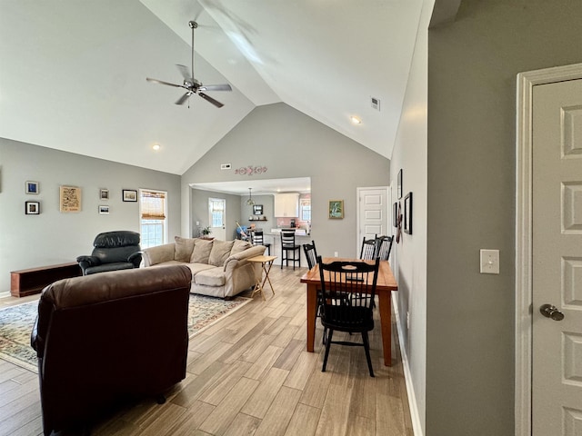 living room with visible vents, a ceiling fan, high vaulted ceiling, light wood-type flooring, and baseboards