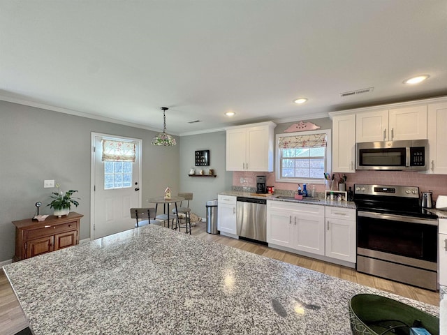 kitchen featuring a sink, visible vents, white cabinets, hanging light fixtures, and appliances with stainless steel finishes