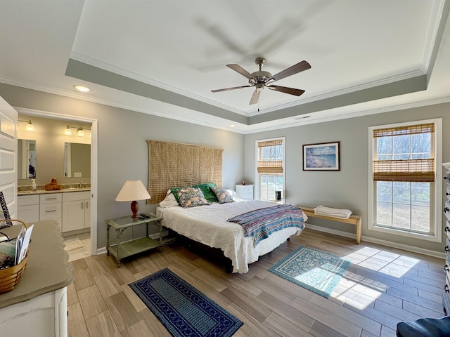 bedroom featuring light wood-style flooring, baseboards, and a raised ceiling