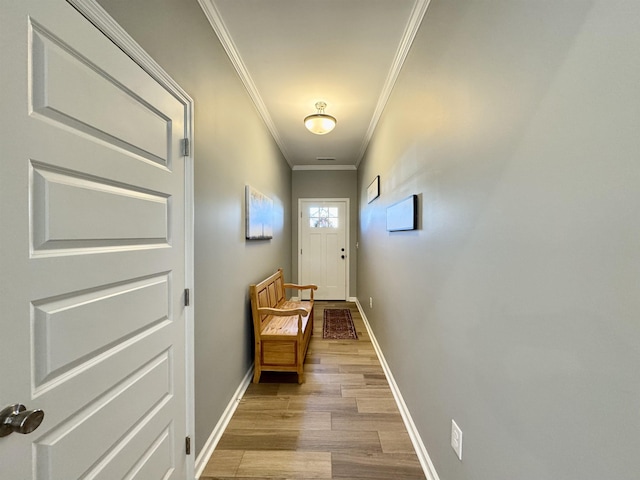 doorway with crown molding, light wood-style floors, and baseboards