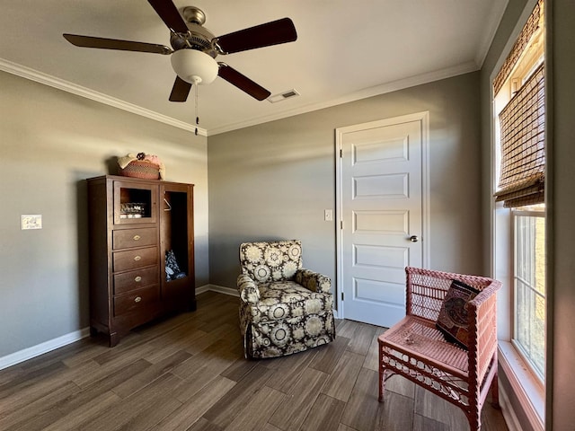 sitting room with dark wood-style floors, visible vents, a wealth of natural light, and ornamental molding