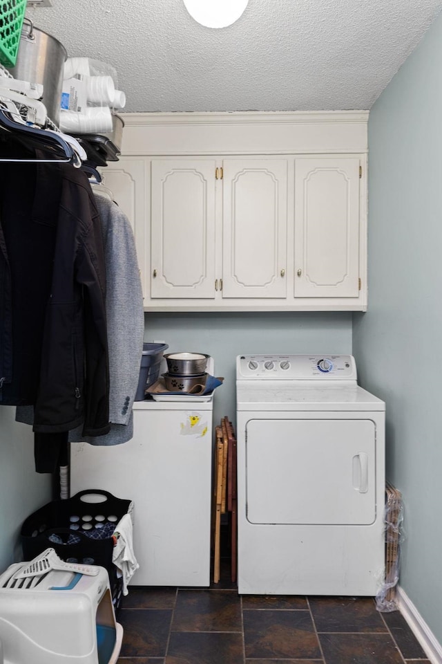 laundry room with cabinet space, baseboards, stone finish flooring, a textured ceiling, and washer and dryer