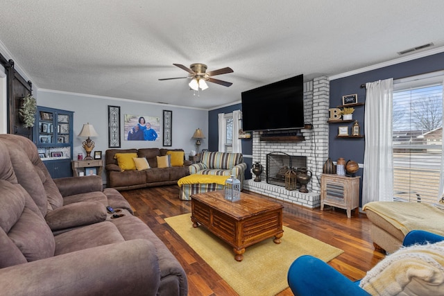 living area with a barn door, visible vents, and crown molding