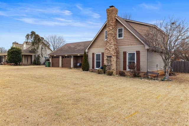 view of front of property with an attached garage, a chimney, fence, and a front lawn