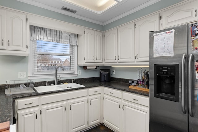 kitchen with stainless steel fridge, visible vents, white cabinets, dark countertops, and a sink