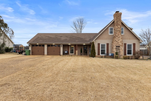 view of front facade featuring a front yard, driveway, a chimney, and an attached garage