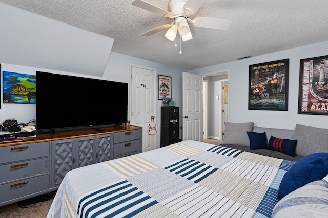 bedroom with ceiling fan, visible vents, dark colored carpet, and a textured ceiling