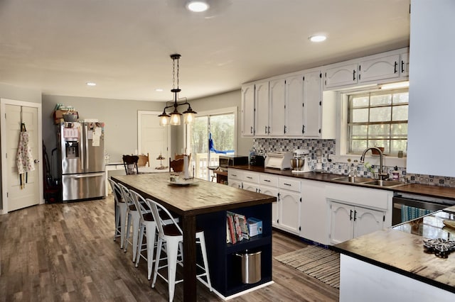 kitchen with a center island, sink, appliances with stainless steel finishes, decorative light fixtures, and white cabinetry