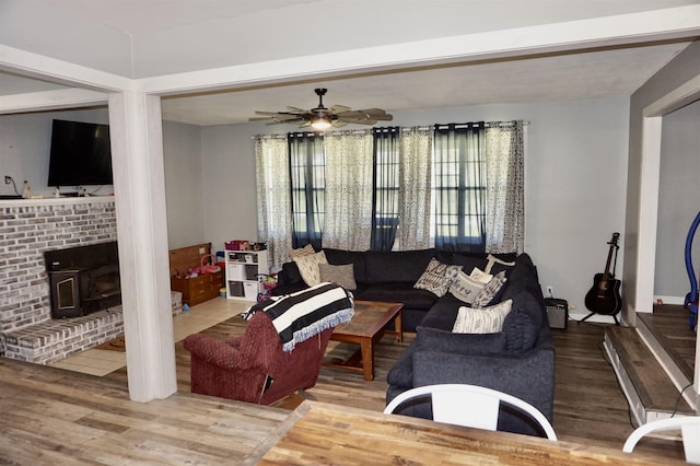 living room with hardwood / wood-style floors, a wood stove, and ceiling fan