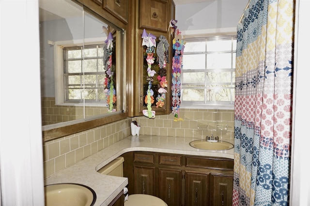 bathroom with tasteful backsplash, vanity, and a healthy amount of sunlight