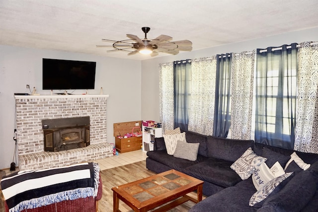 living room featuring ceiling fan, wood-type flooring, and a wood stove