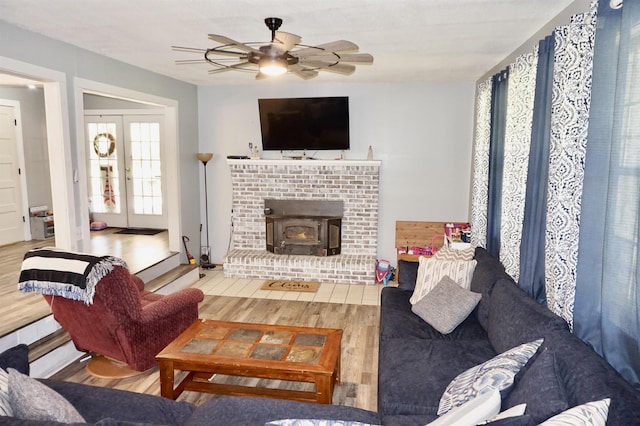 living room featuring french doors, hardwood / wood-style flooring, a wood stove, and ceiling fan