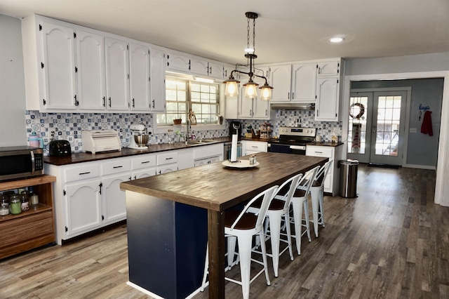 kitchen featuring butcher block counters, white cabinetry, a center island, sink, and appliances with stainless steel finishes