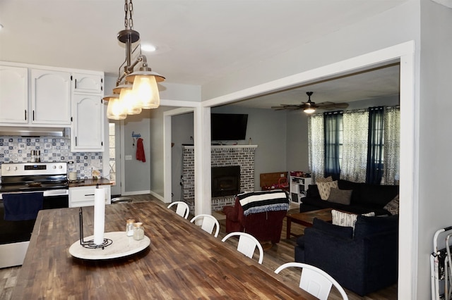 dining room featuring ceiling fan, dark hardwood / wood-style flooring, and a fireplace