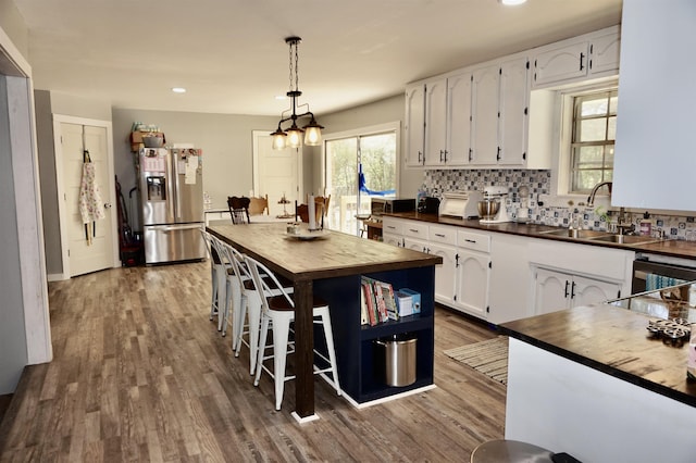 kitchen with white cabinetry, stainless steel fridge with ice dispenser, sink, and wooden counters