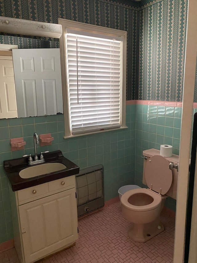 bathroom with vanity, toilet, and tile walls