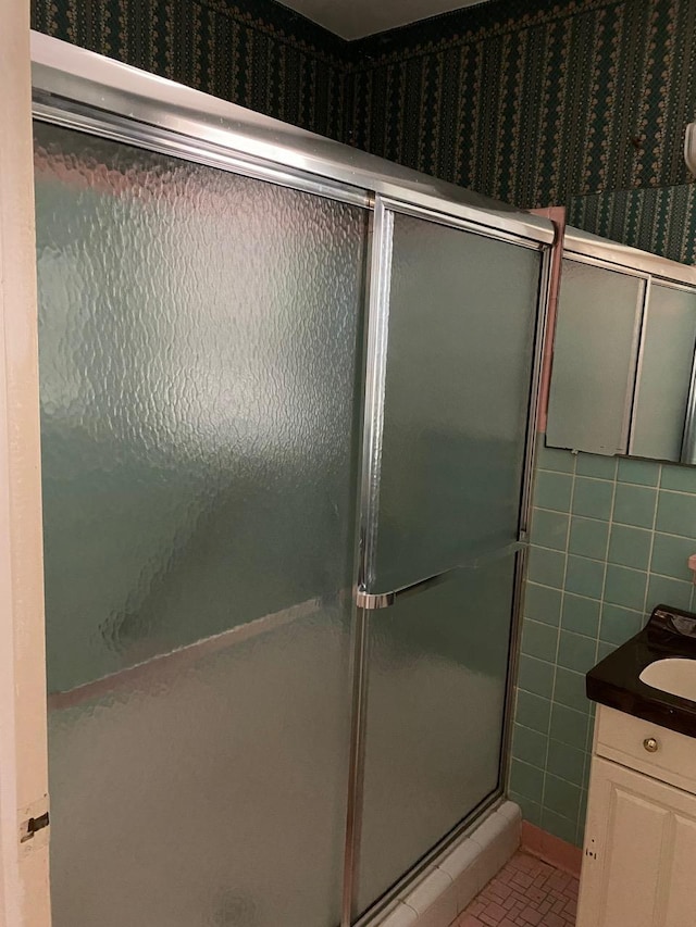 bathroom featuring tile patterned floors, vanity, tile walls, and walk in shower