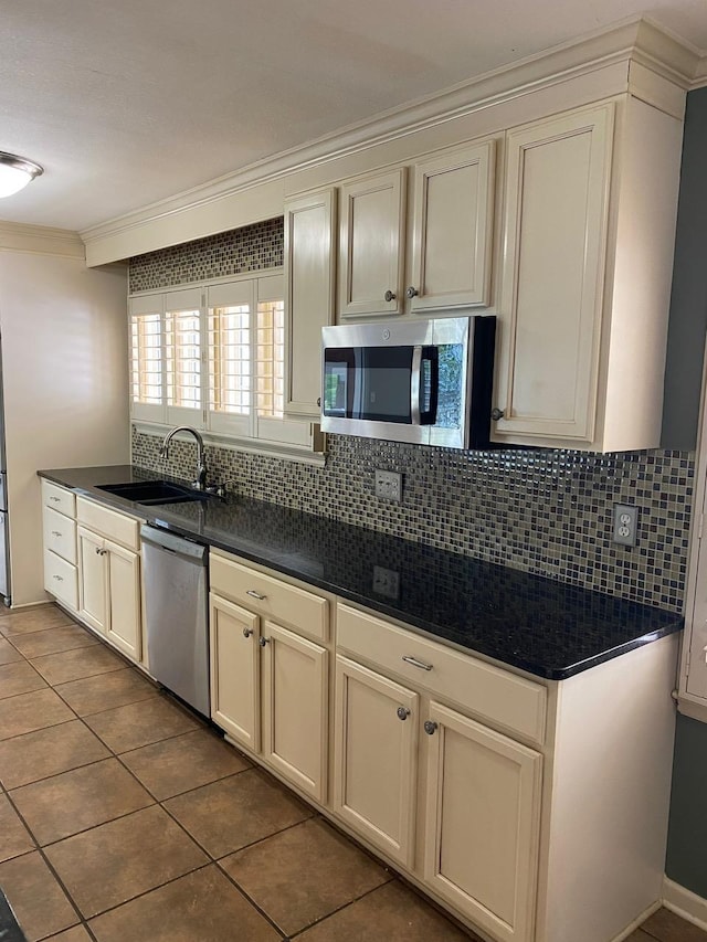 kitchen with sink, stainless steel appliances, backsplash, tile patterned floors, and crown molding