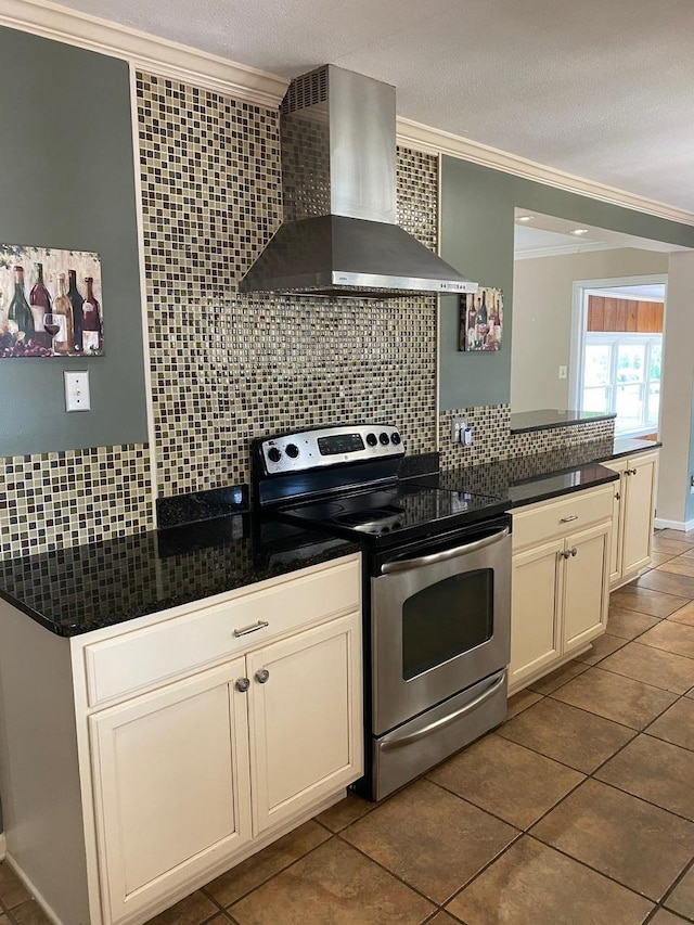 kitchen featuring wall chimney exhaust hood, dark tile patterned floors, crown molding, stainless steel range with electric stovetop, and decorative backsplash