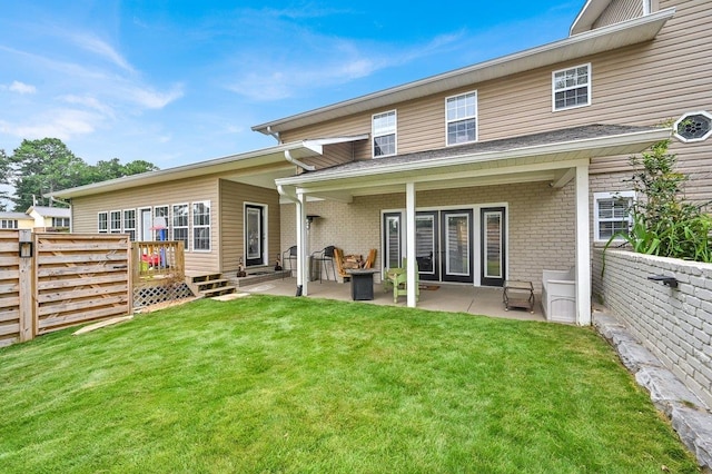 back of property with a yard and a patio