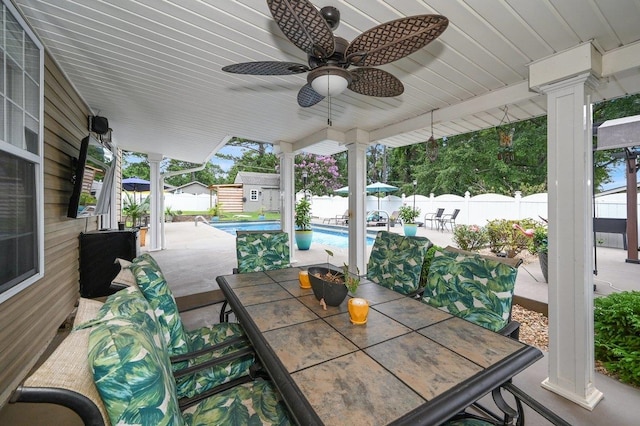 view of patio with a fenced in pool, a storage unit, and ceiling fan