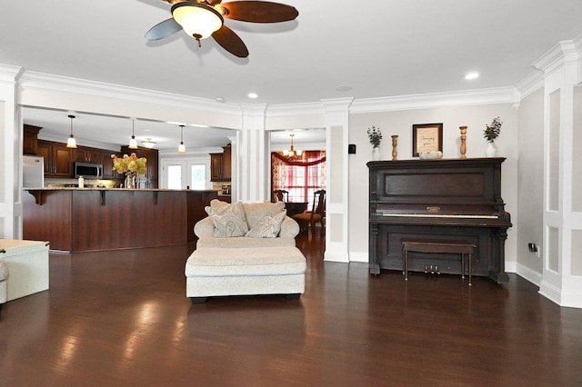 sitting room with ceiling fan with notable chandelier, dark hardwood / wood-style floors, crown molding, and decorative columns