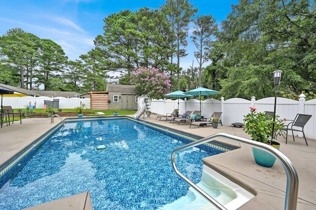 view of pool featuring a patio, a storage unit, and a water slide