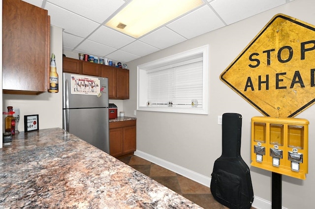 kitchen featuring stainless steel fridge and a drop ceiling