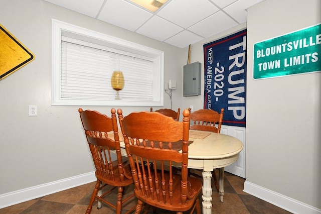 dining room featuring electric panel and a drop ceiling