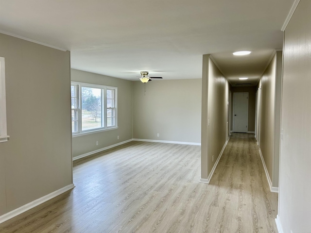 unfurnished room featuring ceiling fan, crown molding, light wood-style flooring, and baseboards