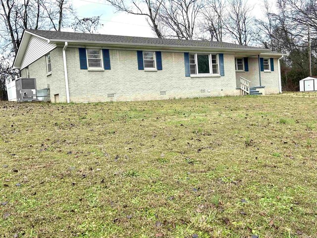 ranch-style home with entry steps, crawl space, brick siding, and a front lawn