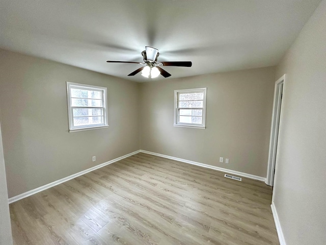 empty room with a ceiling fan, light wood-type flooring, visible vents, and baseboards