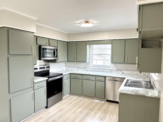 kitchen featuring light wood-style flooring, appliances with stainless steel finishes, ornamental molding, light countertops, and green cabinetry