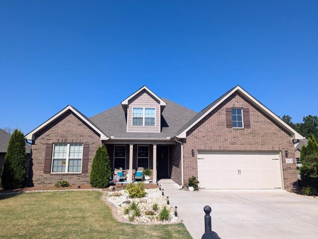 view of front of home featuring a front lawn, covered porch, and a garage