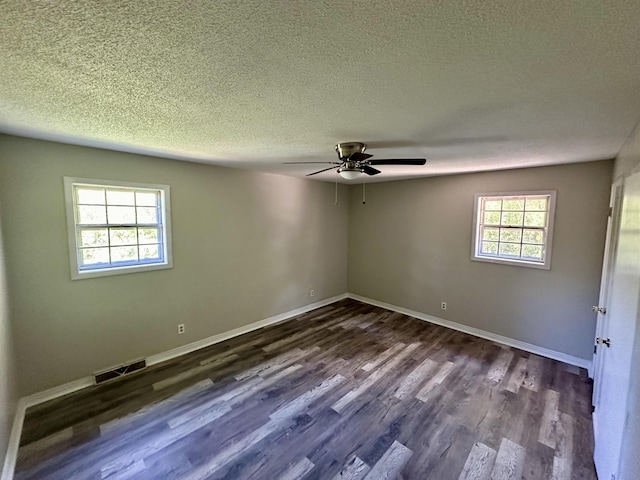 unfurnished room with a textured ceiling, dark wood-type flooring, and a healthy amount of sunlight